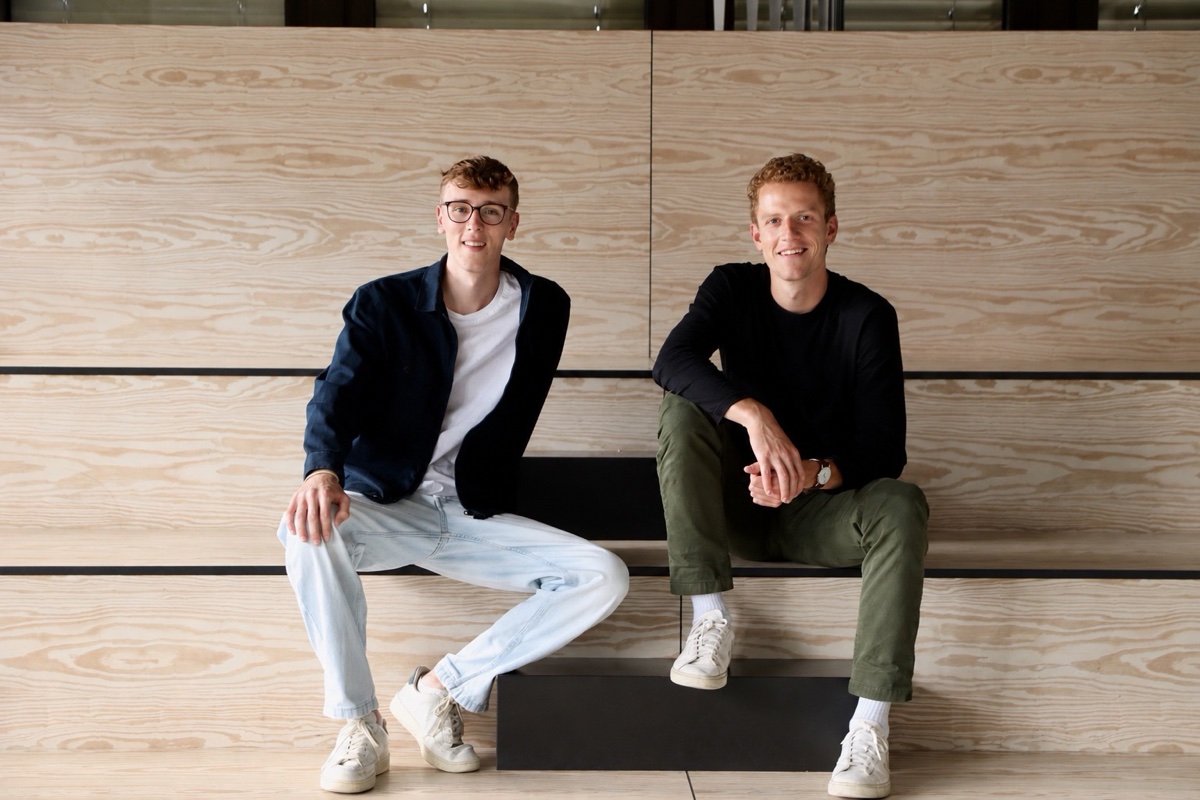 Die better bites Gründer Mattis Sippel und Nico Nonnen sitzen lächelnd auf einer hellen Holztreppe, Teamfoto zum StartupValley-Interview